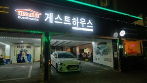 A guesthouse entrance with a neon sign, a mural, and a parked car. - Kimchee Busan Downtown Guesthouse - Hostel (Busan)