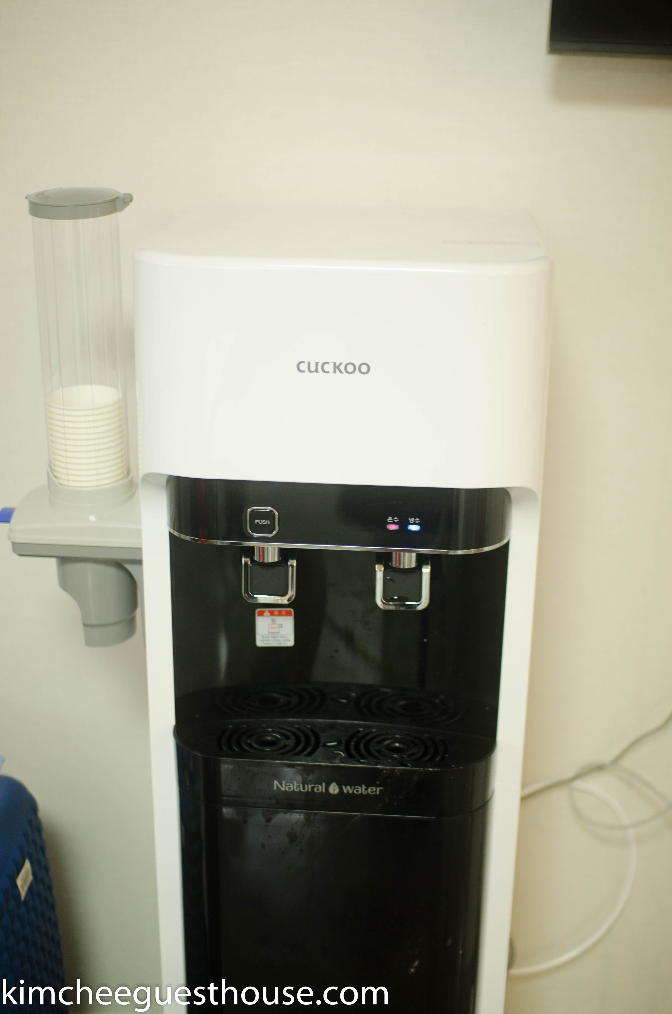 A Cuckoo water dispenser with a push button and a bottle filler, labeled "Natural Water".