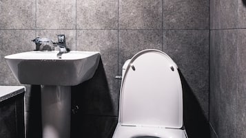 A modern bathroom with a white sink, a toilet, and a hand dryer.