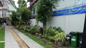 A pathway lined with potted plants and a banner for Harbour Garden Tourist Inn. - Harbour Gardens Tourist Inn (Tagbilaran)