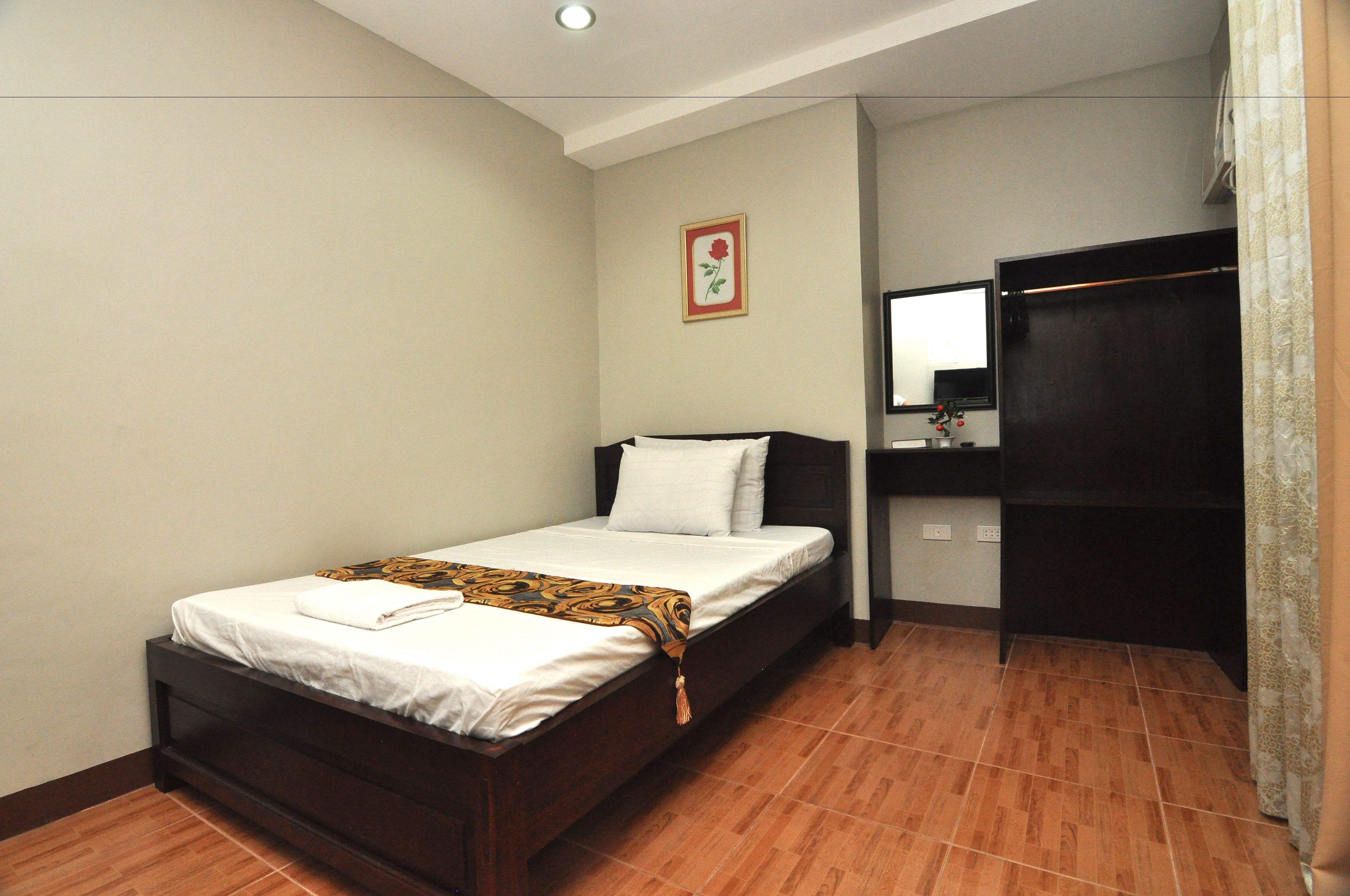 Un dormitorio con una cama, un espejo, un armario y un cuadro en la pared.