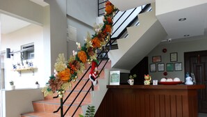 A staircase with a festive garland, a reception desk, and a sign indicating quiet time. - Harbour Gardens Tourist Inn (Tagbilaran)