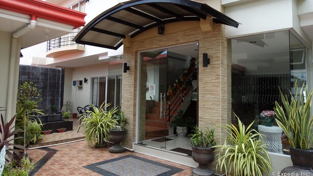 A modern house with a covered entrance, potted plants, and a staircase leading to an upper floor. - Harbour Gardens Tourist Inn (Tagbilaran)