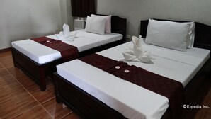 A hotel room with two beds, each with white linens and a red throw blanket. There are three framed artworks on the wall. - Harbour Gardens Tourist Inn (Tagbilaran)