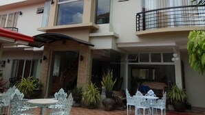 A multi-story building with a balcony, outdoor seating area, and potted plants. - Harbour Gardens Tourist Inn (Tagbilaran)
