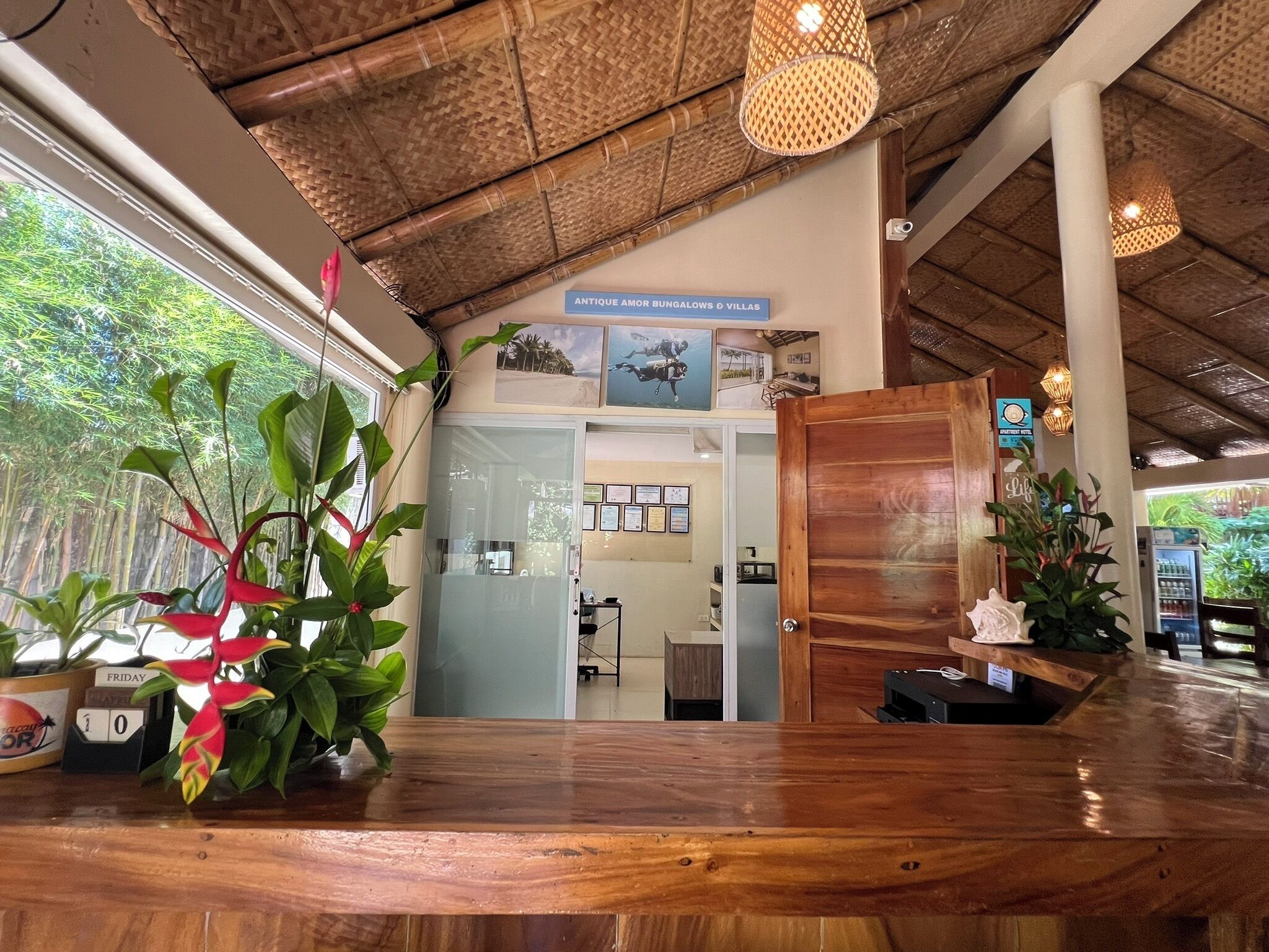 A reception desk with a wooden finish, a glass door leading to a room, and a ceiling with a woven pattern.