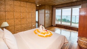 Een hotelkamer met een groot bed, uitzicht op zee en een wand met een bamboepatroon.