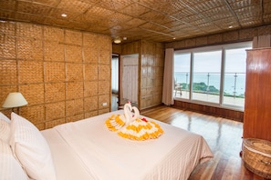 A hotel room with a large bed, a view of the sea, and a bamboo-patterned wall. - Boracay Amor Apartments (Boracay Island)