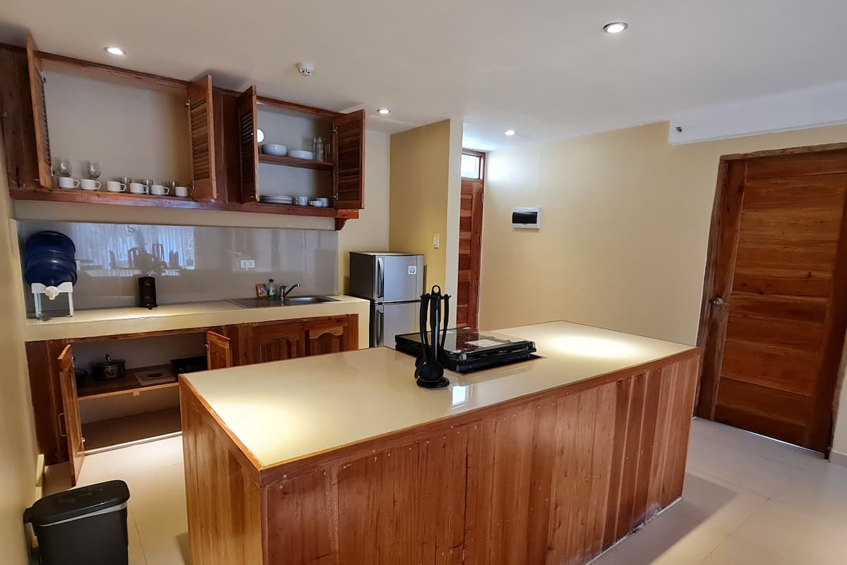 Une cuisine moderne avec des meubles en bois, un îlot central et un réfrigérateur.