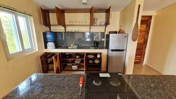 Una cocina con encimeras de granito, estufa a gas, refrigerador y armarios de madera.
