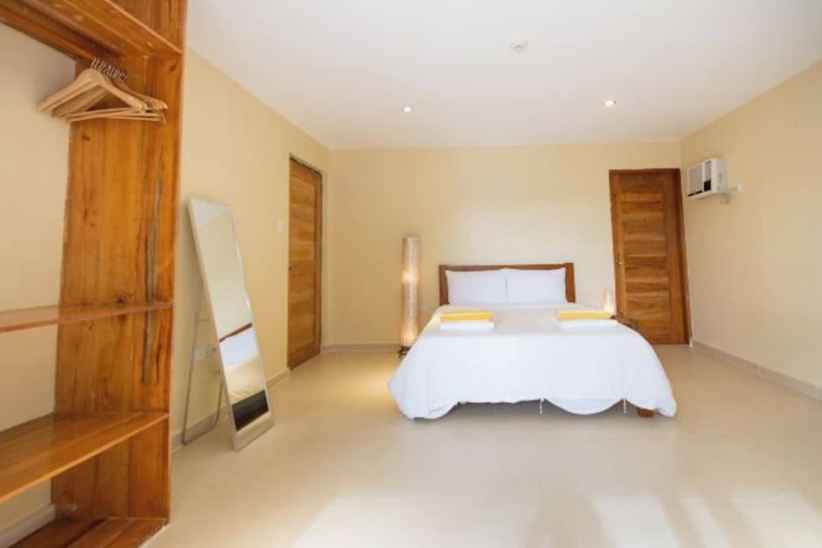 Een slaapkamer met een bed, een houten garderobe en een spiegel.