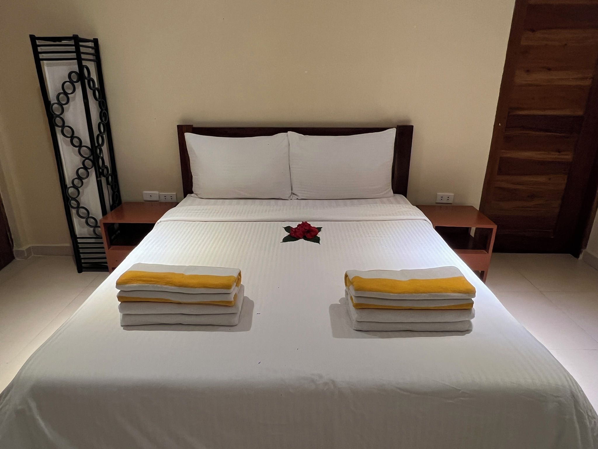 Una cama bien hecha con sábanas blancas y dos toallas dobladas al pie.