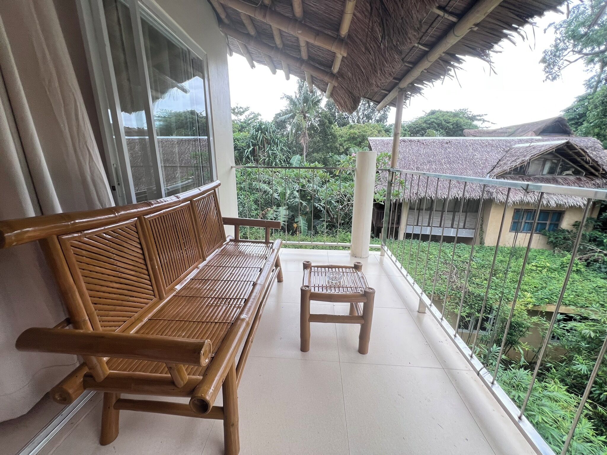 A balcony with a wooden bench and a small table, surrounded by a metal railing.