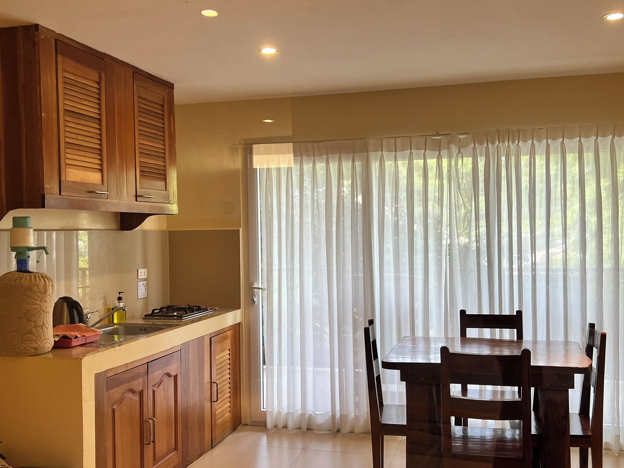 A kitchen with wooden cabinets, a gas stove, and a dining table with chairs.
