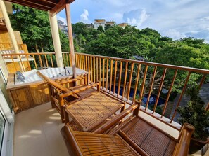 Un balcon agrémenté de meubles en bois, un jacuzzi et une vue sur un paysage verdoyant luxuriant.