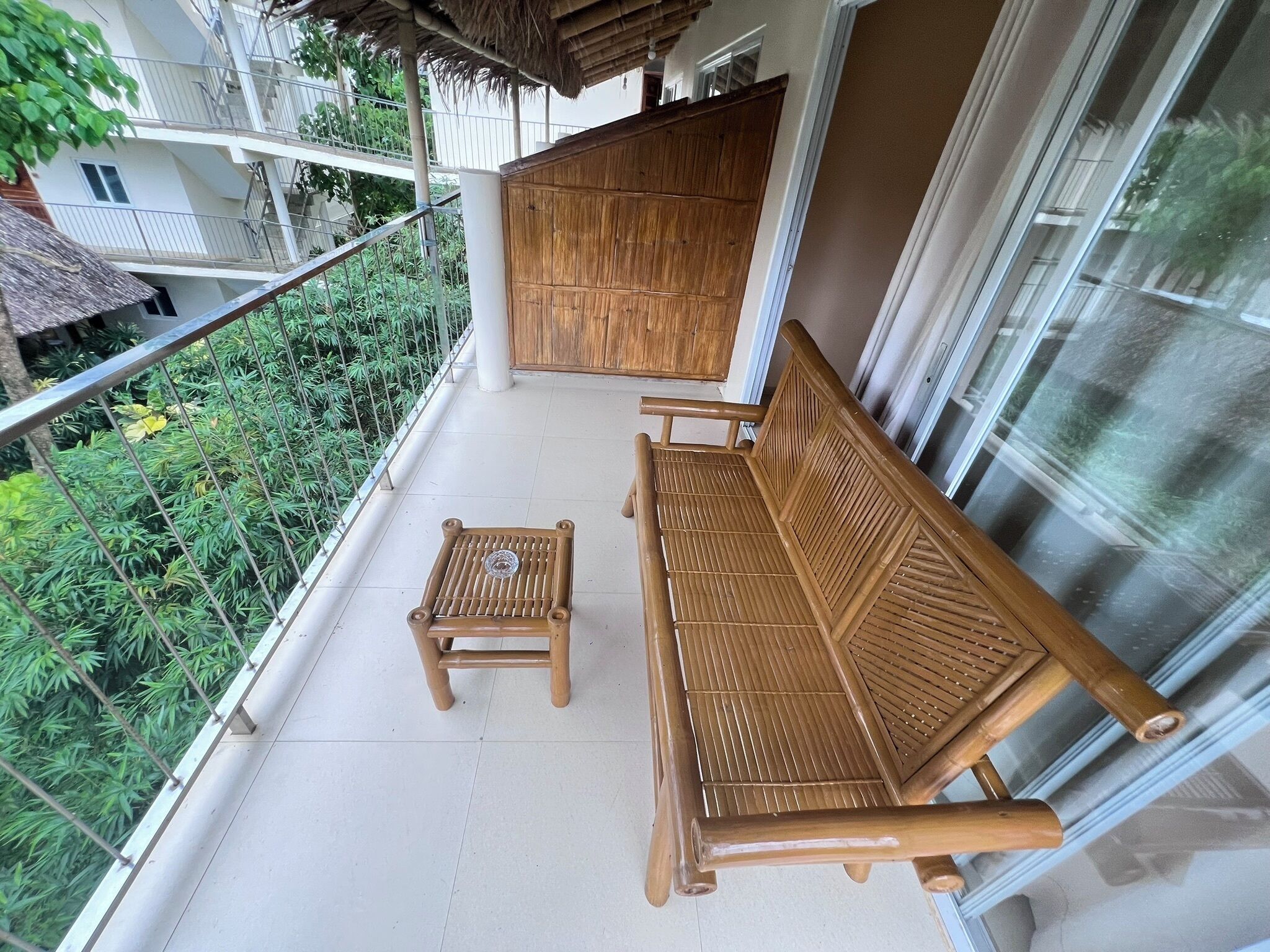 A balcony with a wooden bench and a small table, surrounded by a metal railing.