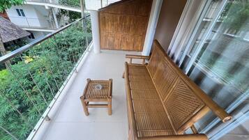 A balcony with a wooden bench and a small table, surrounded by a metal railing.