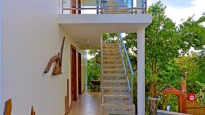 Une maison moderne dotée d’un intérieur spacieux, d’un escalier menant à un balcon et offrant une vue sur l’extérieur.
