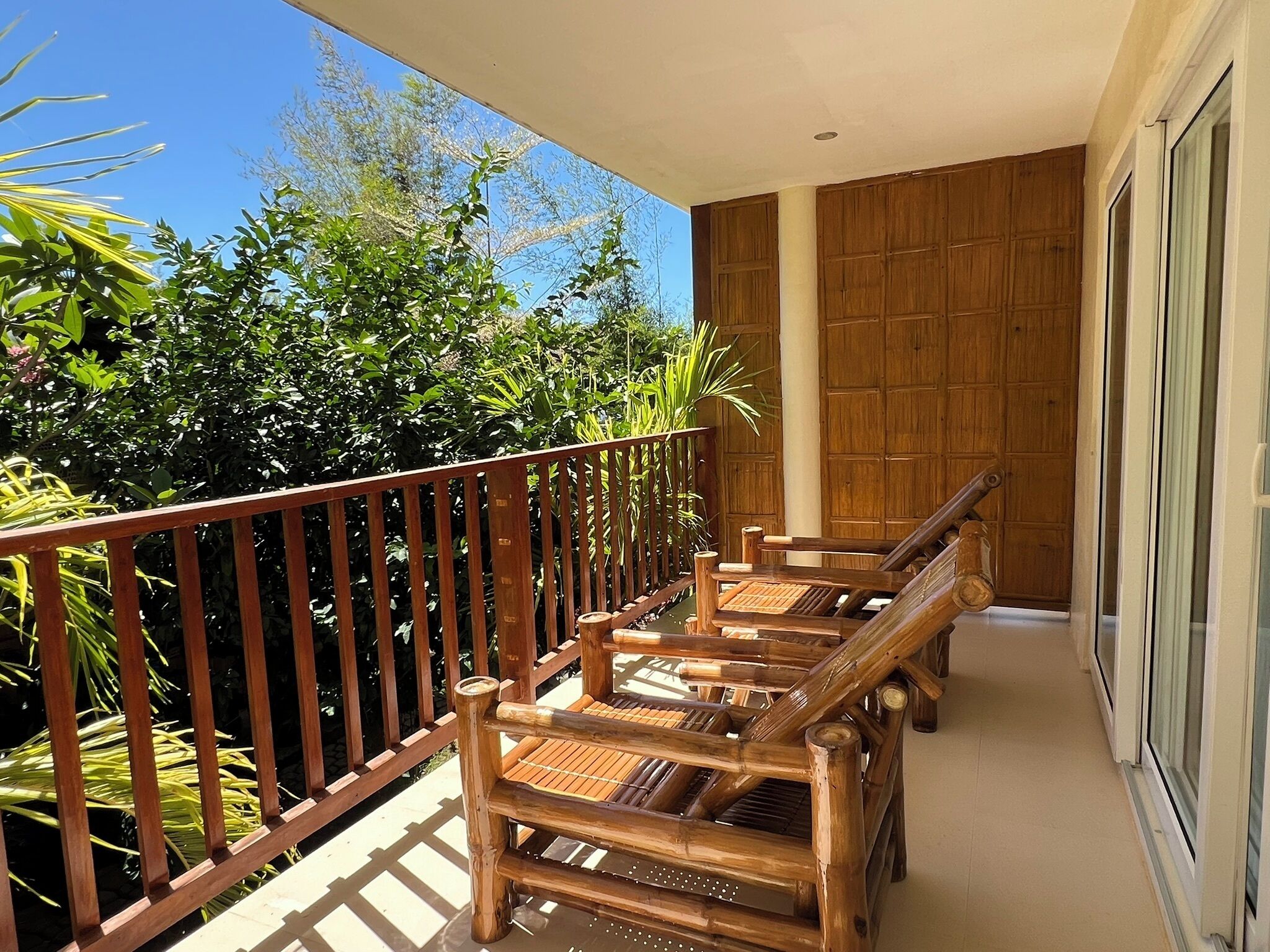 Un balcon doté de mobilier en bois et offrant une vue sur une végétation luxuriante.