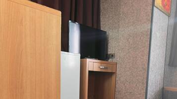 A hotel room with a bed, a small wooden cabinet, a television, and a decorative wall piece.