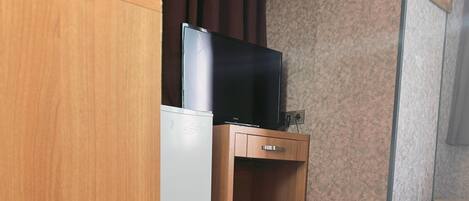 A hotel room with a bed, a small wooden cabinet, a television, and a decorative wall piece.