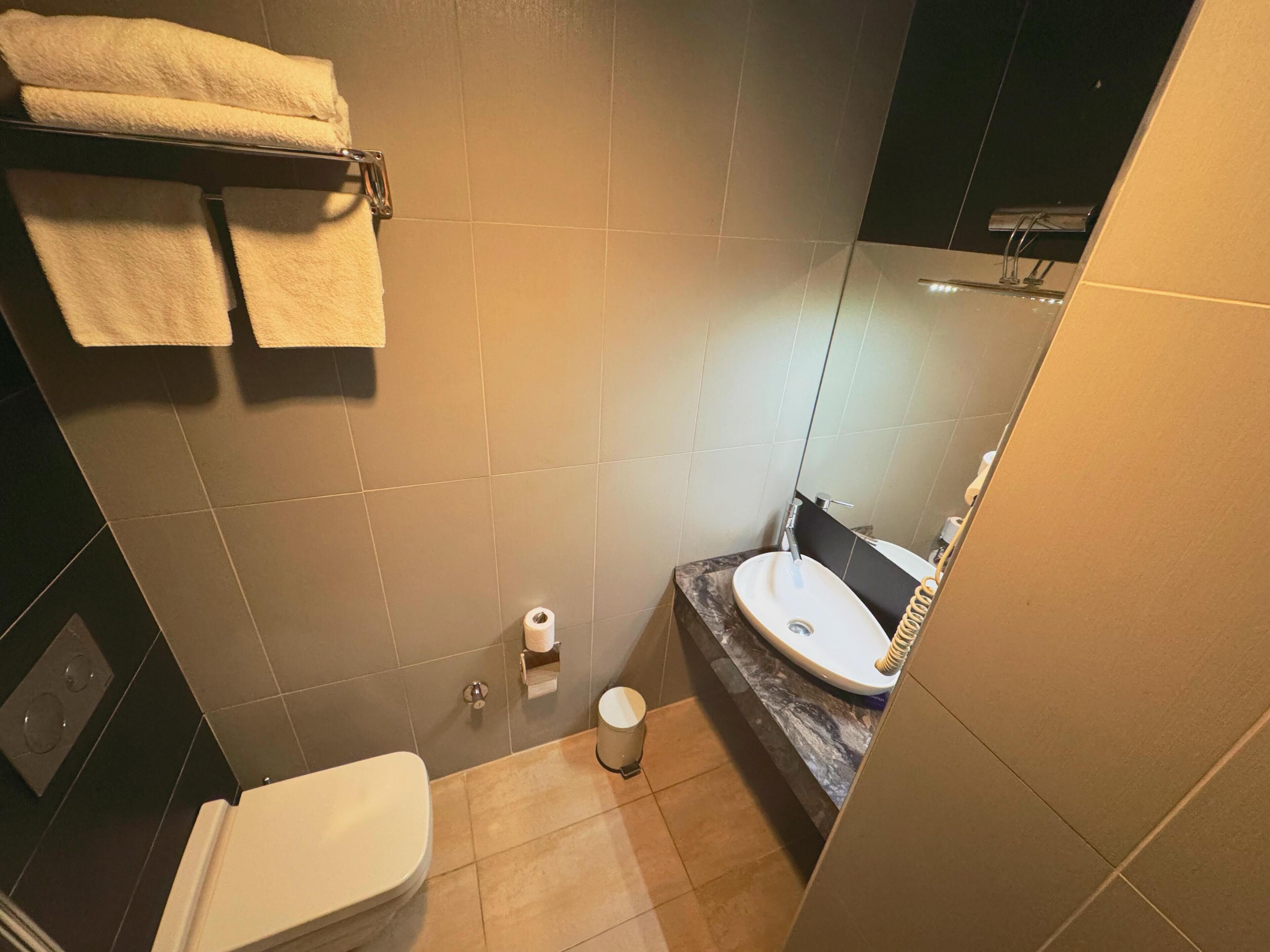 A compact bathroom with a toilet, sink, and a towel rack.