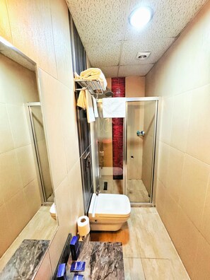 A bathroom with a glass shower enclosure, a toilet, and a towel rack with towels. - Lounge Boutique Hotel (Istanbul)