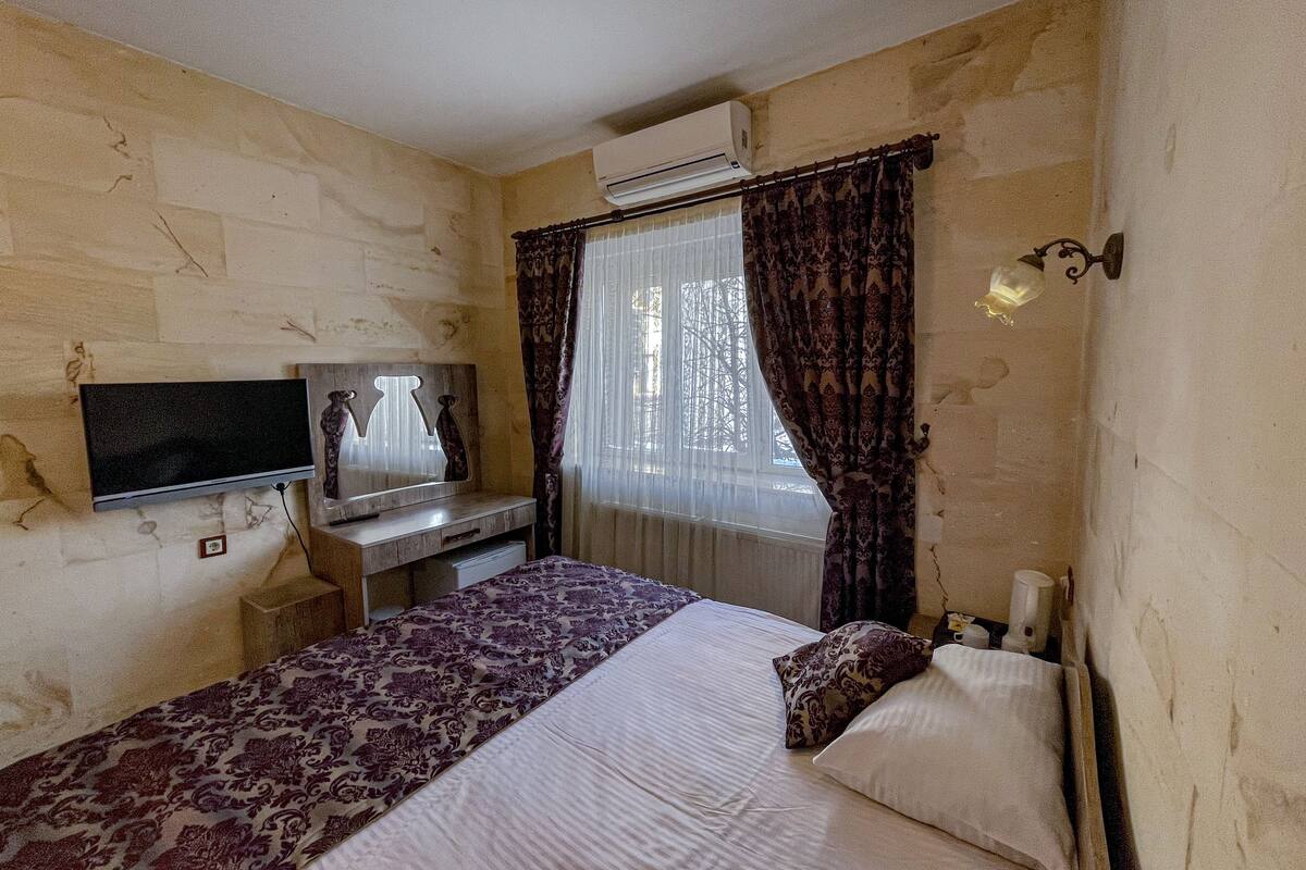 Une chambre d’hôtel équipée d’un lit, d’une télévision, d’un bureau et d’un appareil de climatisation.