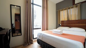 A hotel room with a bed, a desk, a chair, and a window with curtains. - Aliria Bed and Breakfast (Tagbilaran)