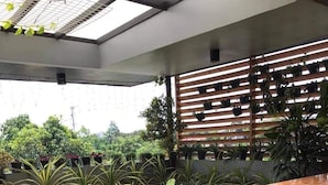 A cozy indoor garden with a wooden bench and a small table surrounded by potted plants. - Aliria Bed and Breakfast (Tagbilaran)