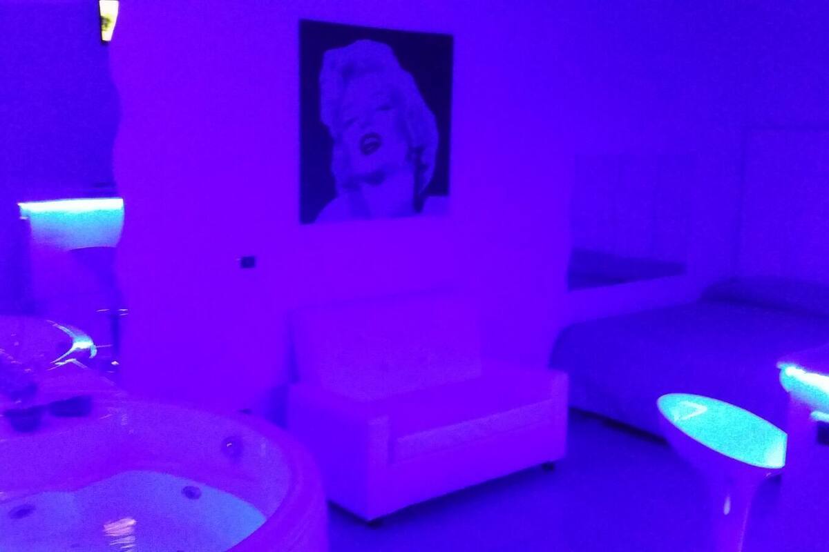 A room with a white sofa, a small table, and a wall-mounted picture.
