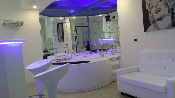 A modern bathroom with a curved sink, white fixtures, and a blue-lit ceiling. - Hotel Joy (Castel Volturno)