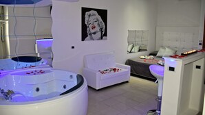 A modern bedroom with a large bed, a separate seating area, and a jacuzzi. - Hotel Joy (Castel Volturno)