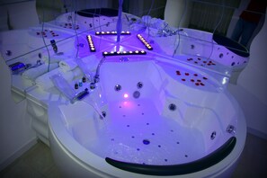 A modern spa with multiple hot tubs, each with a glass partition and LED lighting. - Hotel Joy (Castel Volturno)