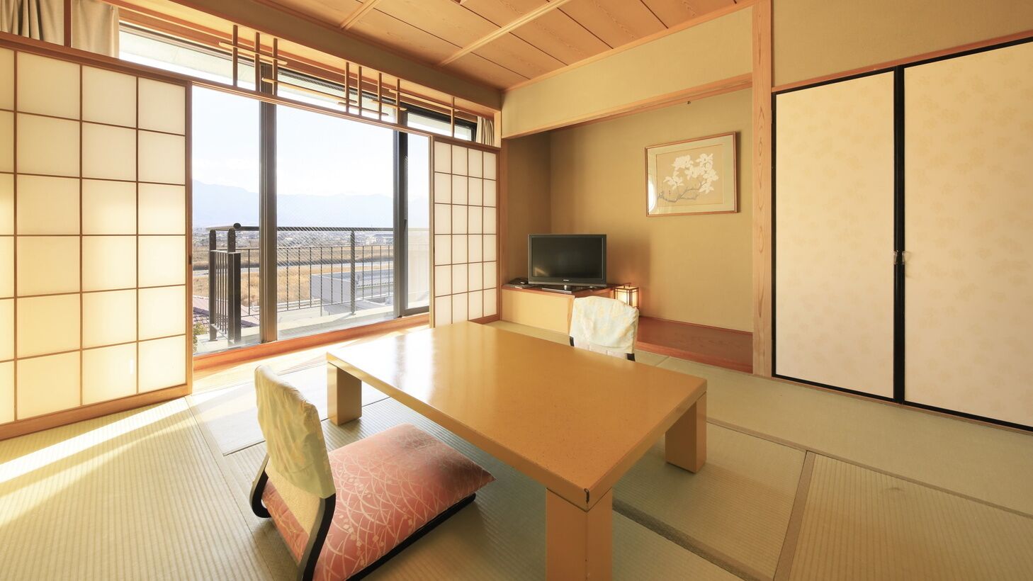 A traditional Japanese room with tatami flooring, a low table, a cushioned bench, a television, and a sliding door.
