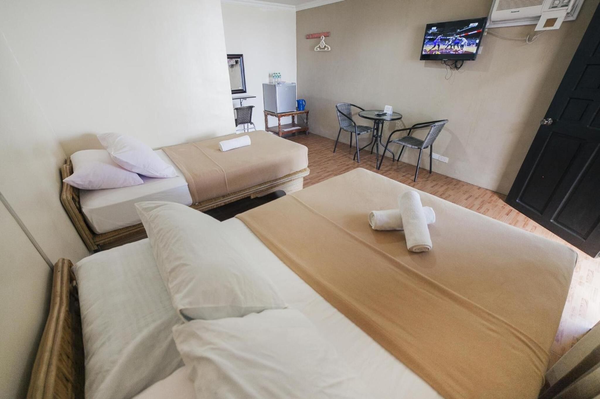 Camera d'albergo con due letti, un tavolino, una TV e una scrivania con una sedia.