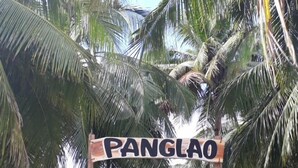 A sign for Panglao Grande Resort with a stone wall and palm trees in the background. - Panglao Grande Resort (Panglao)