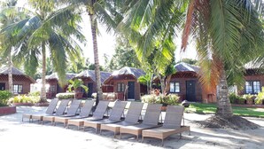 A beachside resort with thatched-roof huts, lounge chairs, and palm trees. - Panglao Grande Resort (Panglao)