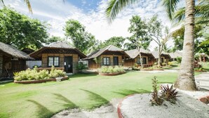 A resort with thatched-roof huts, well-maintained lawns, and tropical plants. - Panglao Grande Resort (Panglao)