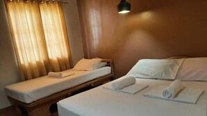 A room with two single beds, each with a rolled towel, a wooden headboard, and a bedside table. - Panglao Grande Resort (Panglao)
