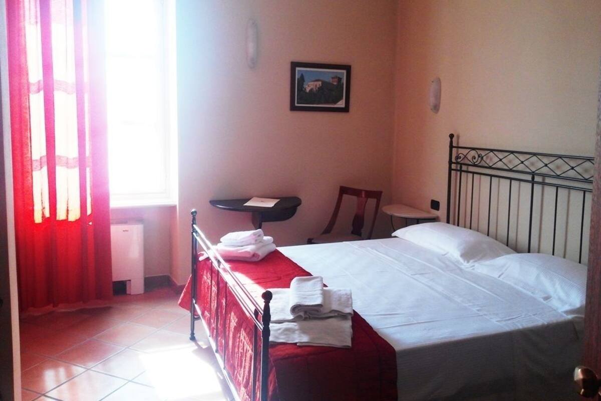 A hotel room with a bed, a desk, a chair, and a small table.