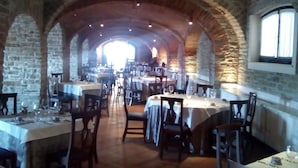 Un restaurant doté d’arches en pierre, de tables dressées pour le service et offrant une vue sur la salle à manger.