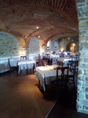 A restaurant with stone walls and arched ceilings, tables set for dining, and a rustic ambiance. - Il Castello di Bubbio (Bubbio)