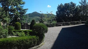 Une rue pavée bordée d’un beau parterre et ornée d’une statue.