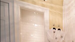 A bathroom with a white door, a towel rack with two white towels, and a shower curtain. - Islay House (Islay Island)