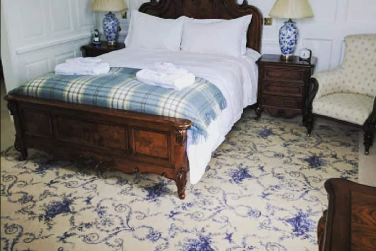 Un dormitorio tradicional con una cama de madera, una mesita de noche a juego, una silla y un suelo con diseño.