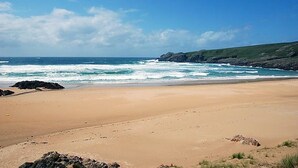 A beach with a clear sky, waves, and rocky outcrops. - Islay House (Islay Island)