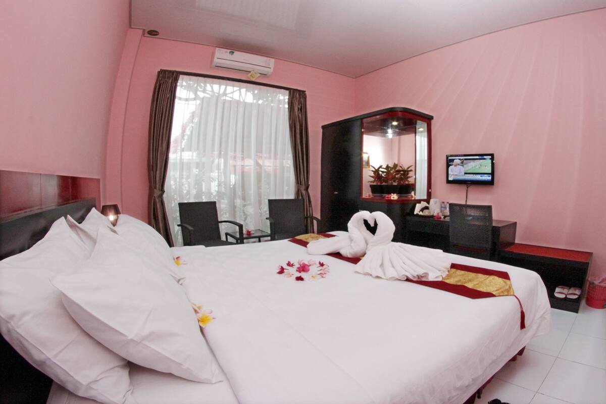 Ein Hotelzimmer mit einem ordentlich bezogenen Bett, einem Fernseher, einem Schreibtisch und einem Stuhl.