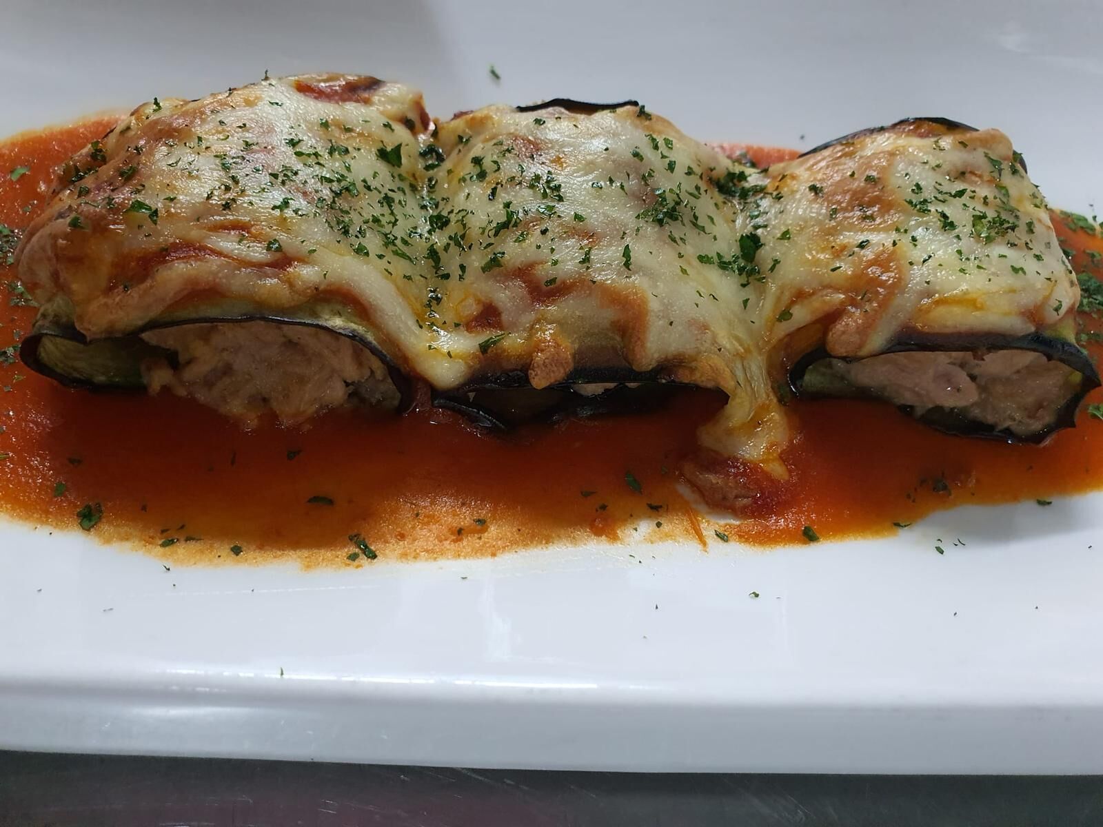 A dish of stuffed zucchini with cheese and tomato sauce.