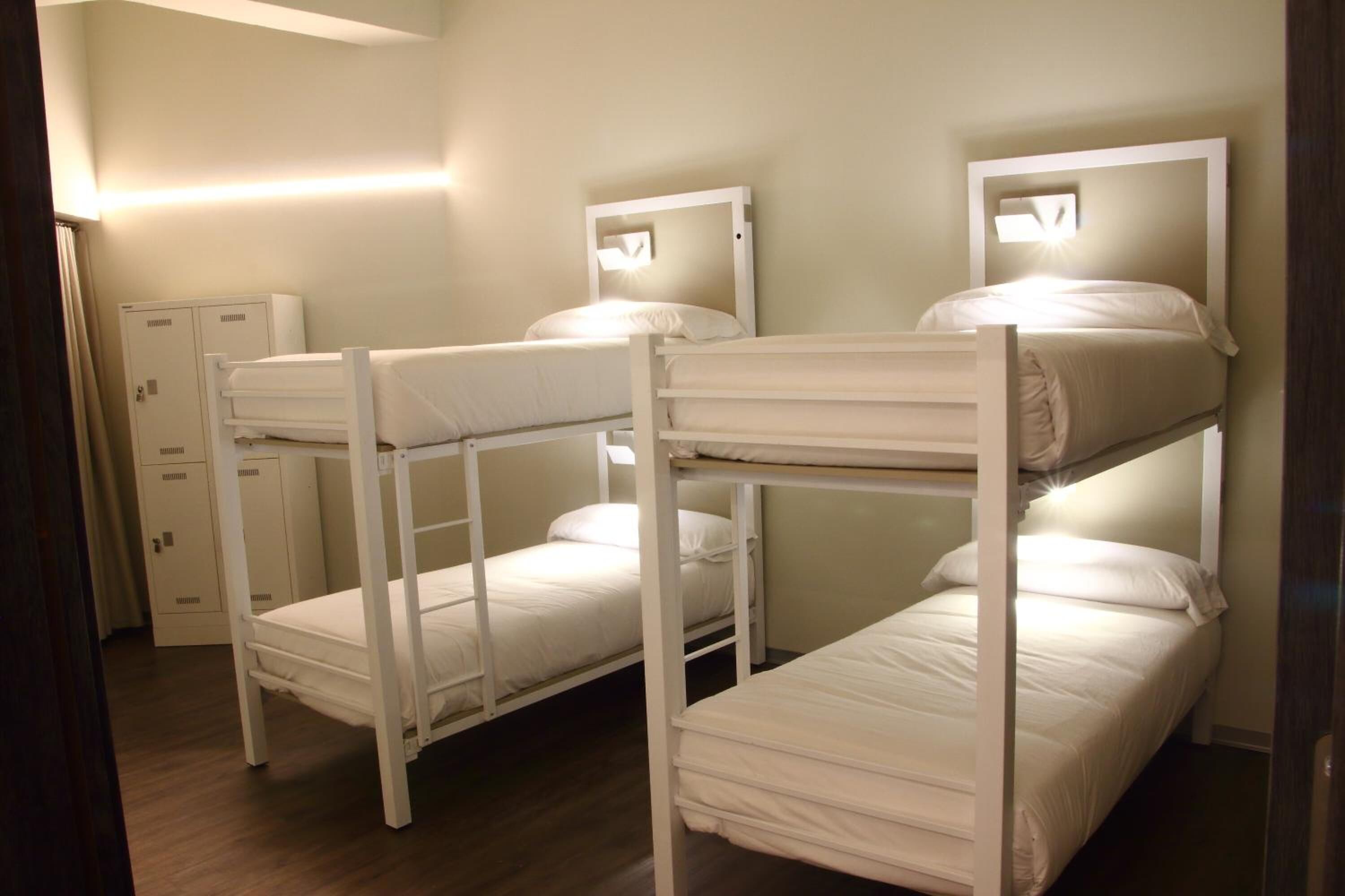 Een kamer met stapelbedden, een garderobe en een wandlamp.